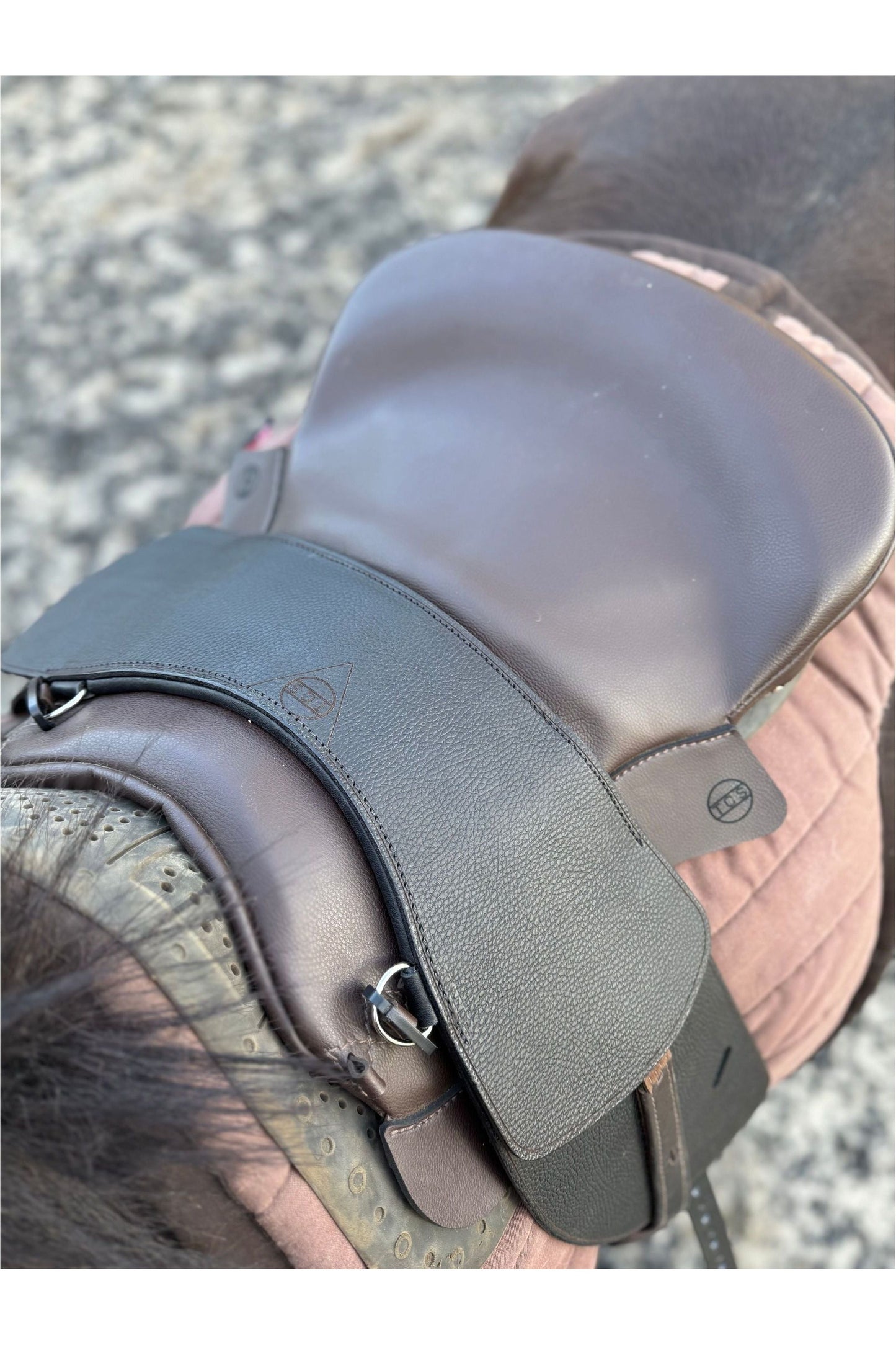 A treeless total contact saddle and a TCS saddle seat pad combination on a bay horse, viewed from above as if standing on a mounting block, about to get on