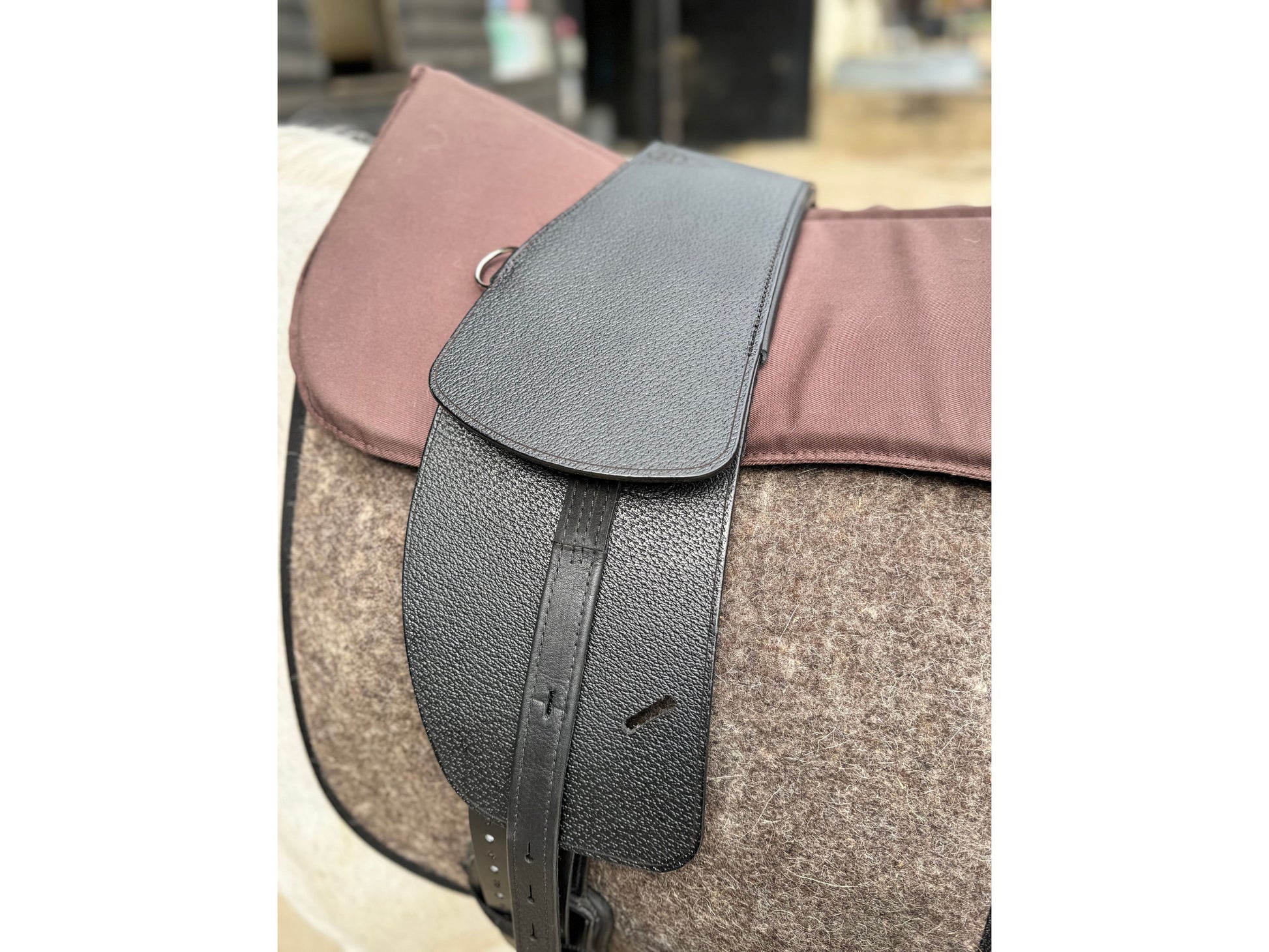 A Premium black short billet TCS saddle with black TCS webbers on a grey horse wearing a felt saddle pad and a brown half pad