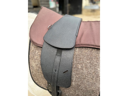 A Premium black short billet TCS saddle with black TCS webbers on a grey horse wearing a felt saddle pad and a brown half pad