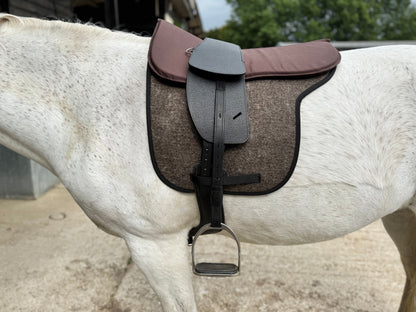 A Premium black short billet TCS saddle with black TCS webbers on a grey horse wearing a felt saddle pad and a brown half pad