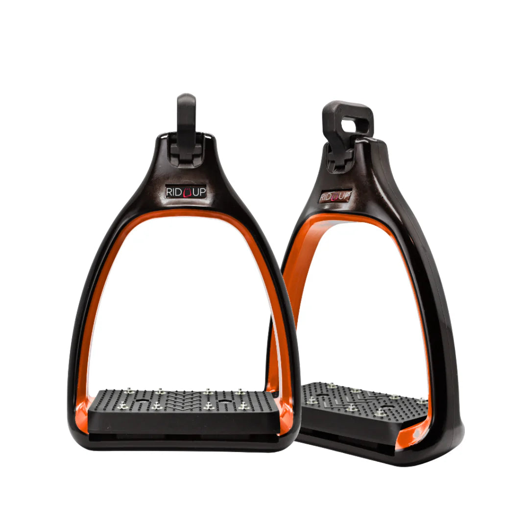 A pair of black and orange Rid'Up horse riding stirrups with bright orange inner accents and textured black footbeds, shown against a plain white background.