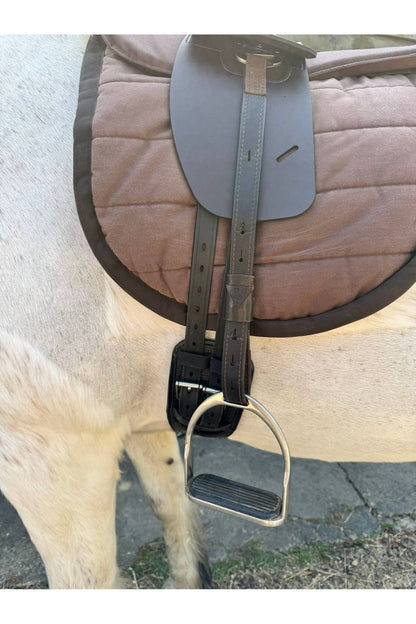 A synthetic chocolate brown Total Contact Saddle close up on a brown saddle pad and a brown half pad on a grey pony