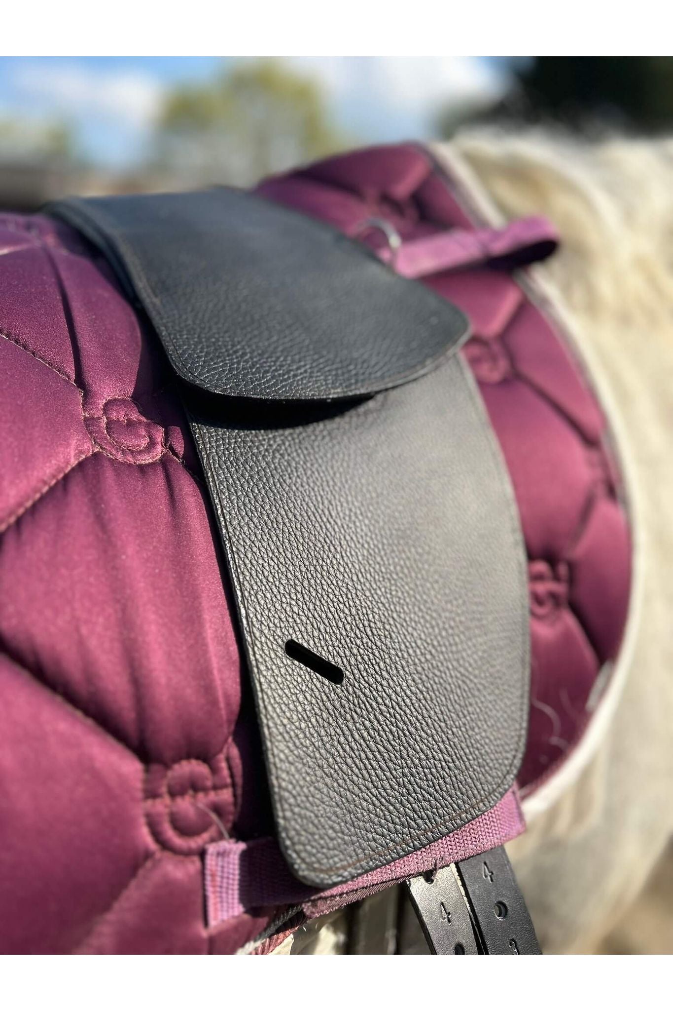 A classic black short billet treeless Total Contact Saddle on a pink saddle pad on a grey pony