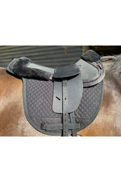 A premium black total contact treeless saddle on a dark bay horse wearing a black addle pad and a black half pad