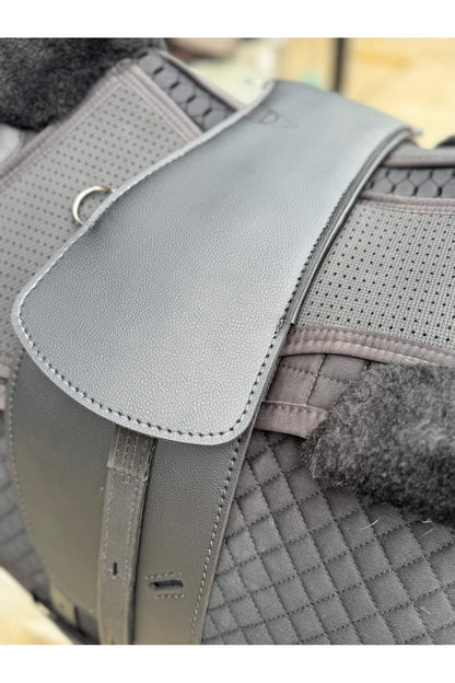 A synthetic black long billet Total Contact Saddle close up on a black saddle pad and a black half pad 