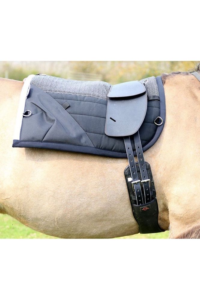 A classic total contact treeless saddle on a dun horse with no stirrup leathers and a black saddle pad